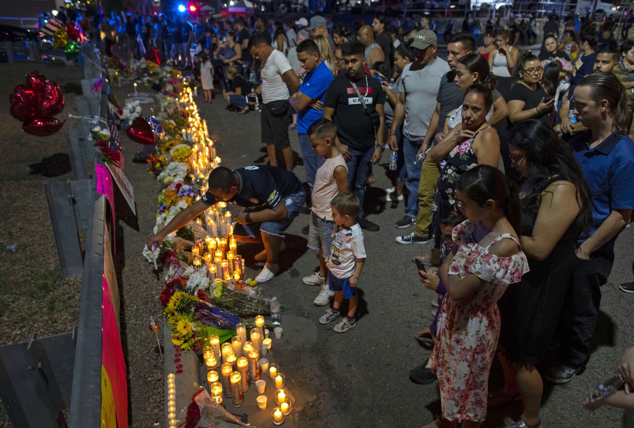 People gather at makeshift memorial for the victims of Saturday's mass shooting at a shopping complex in El Paso, Texas, Sunday, Aug. 4, 2019.